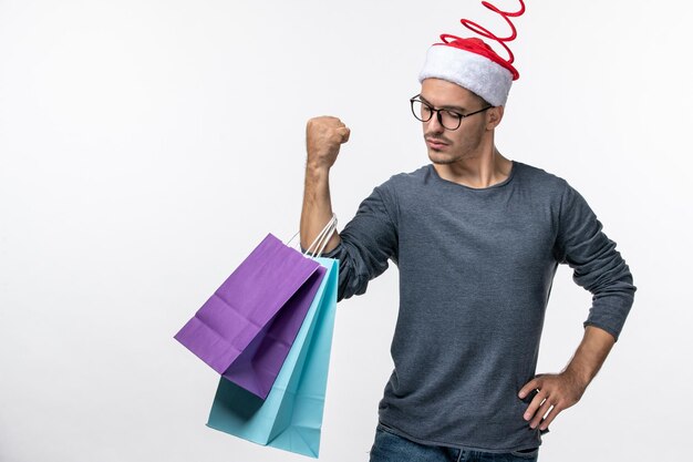 Vista frontal del joven después de las compras navideñas en la pared blanca