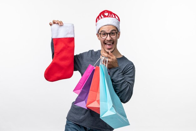 Vista frontal del joven después de las compras navideñas en la pared blanca