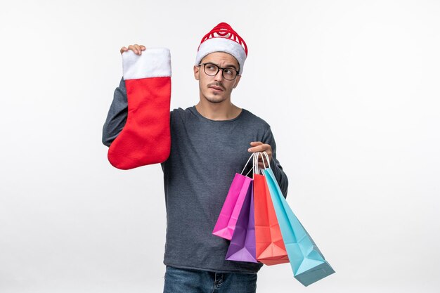 Vista frontal del joven después de las compras navideñas en la pared blanca