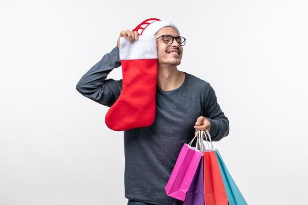 Vista frontal del joven después de las compras navideñas en la pared blanca