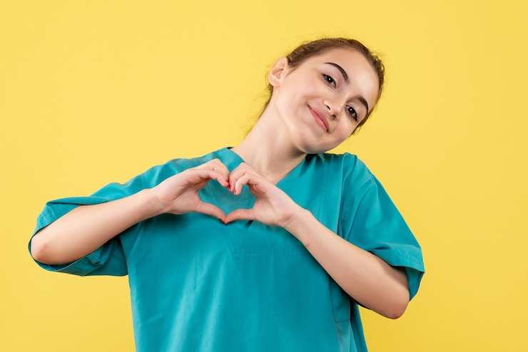 Foto gratuito vista frontal de la joven doctora en camisa médica enviando amor en la pared amarilla