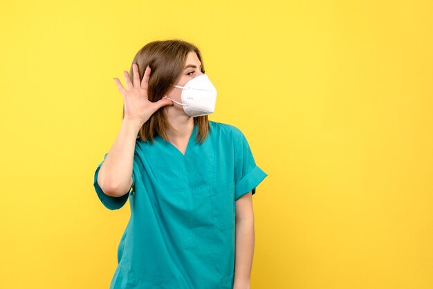 Vista frontal de la joven doctora con máscara en el piso amarillo pandemia médica del hospital