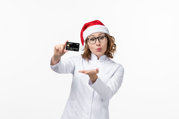 Vista frontal joven doctora sosteniendo una tarjeta bancaria en la pared blanca vacaciones enfermera año nuevo