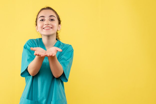 Vista frontal joven doctora en traje médico sobre fondo amarillo