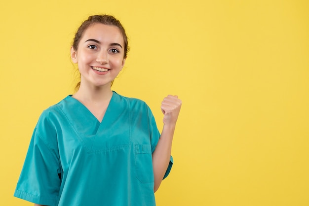 Vista frontal joven doctora en traje médico sobre fondo amarillo