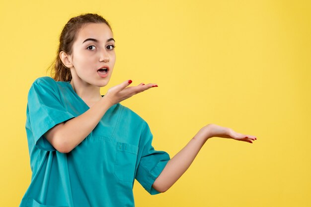 Vista frontal joven doctora en traje médico sobre fondo amarillo