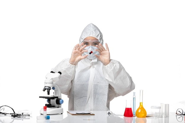 Vista frontal joven doctora en traje de protección blanco con máscara debido a covid trabajando sobre fondo blanco salud del virus pandémico covid