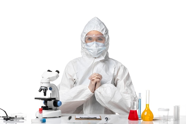 Vista frontal joven doctora en traje protector con máscara debido a covid sobre fondo blanco claro coronavirus del virus covid pandémico