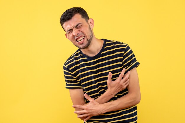 Vista frontal joven en dolor de pie sobre fondo amarillo aislado