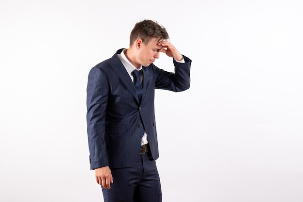 Vista frontal joven en elegante traje clásico con dolor de cabeza sobre fondo blanco.