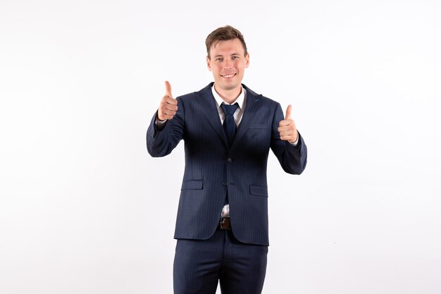 Vista frontal joven en elegante traje clásico posando con sonrisa sobre fondo blanco.