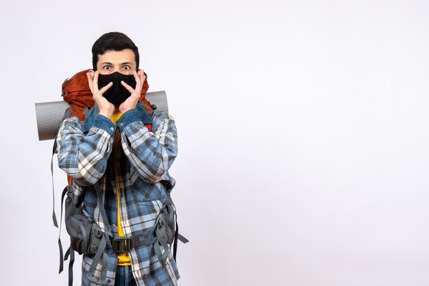 Vista frontal joven excursionista de ojos abiertos con mochila y máscara