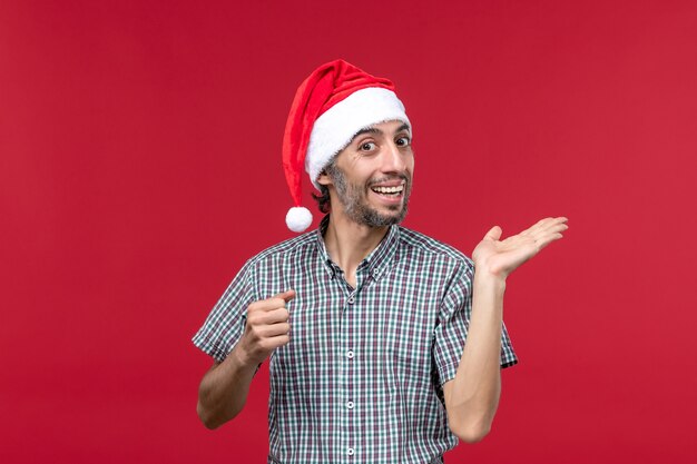 Vista frontal joven con expresión emocionada en la pared roja vacaciones año nuevo rojo masculino