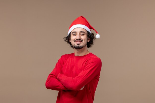 Vista frontal joven con expresión sonriente sobre un fondo marrón vacaciones de emociones navideñas