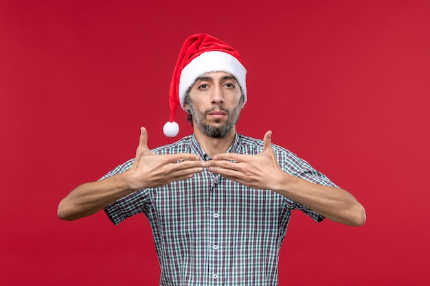 Vista frontal joven con gorro de año nuevo en la pared roja año nuevo rojo vacaciones macho