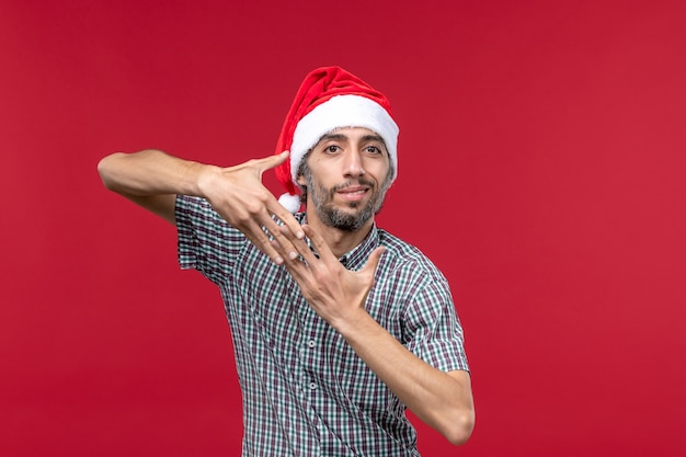 Vista frontal joven con gorro de año nuevo en pared roja vacaciones de año nuevo rojo macho