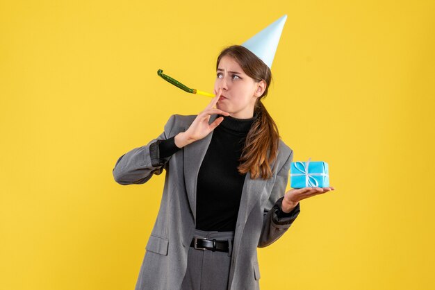 Vista frontal joven con gorro de fiesta sosteniendo su regalo con matraca