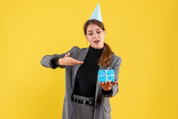 Vista frontal joven con gorro de fiesta sosteniendo su regalo