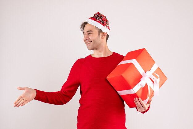 Vista frontal joven con gorro de Papá Noel dando la mano sobre fondo blanco.