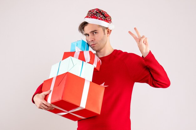 Vista frontal joven con gorro de Papá Noel haciendo el signo de la victoria sobre fondo blanco.