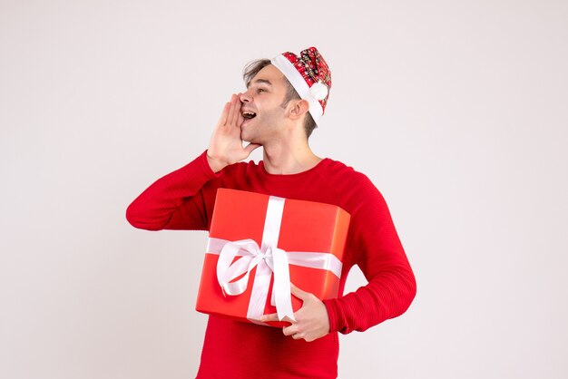 Vista frontal joven con gorro de Papá Noel llamando a alguien sobre fondo blanco.