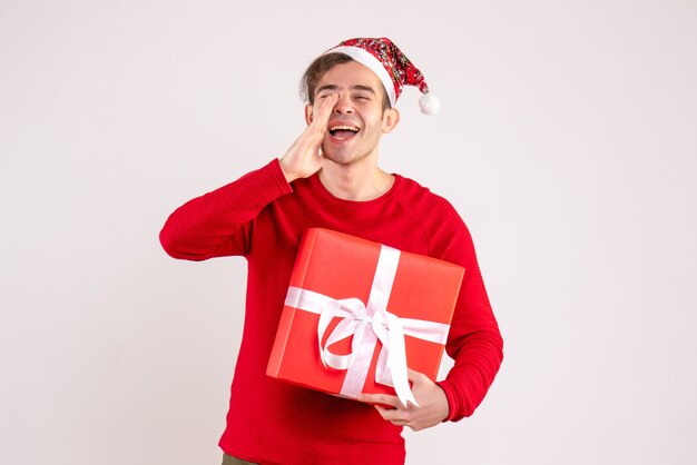 Vista frontal joven con gorro de Papá Noel llamando a alguien sobre fondo blanco.