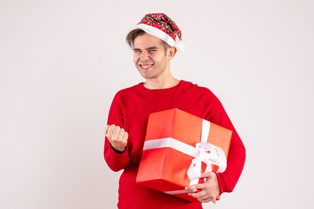 Vista frontal joven con gorro de Papá Noel mostrando gesto ganador sobre fondo blanco.