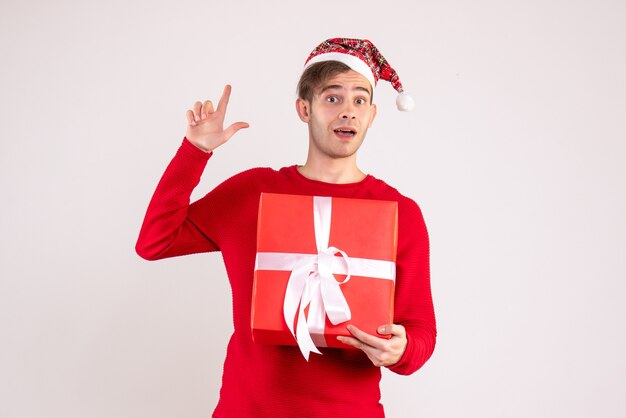 Vista frontal joven con gorro de Papá Noel de pie sobre fondo blanco con espacio de copia