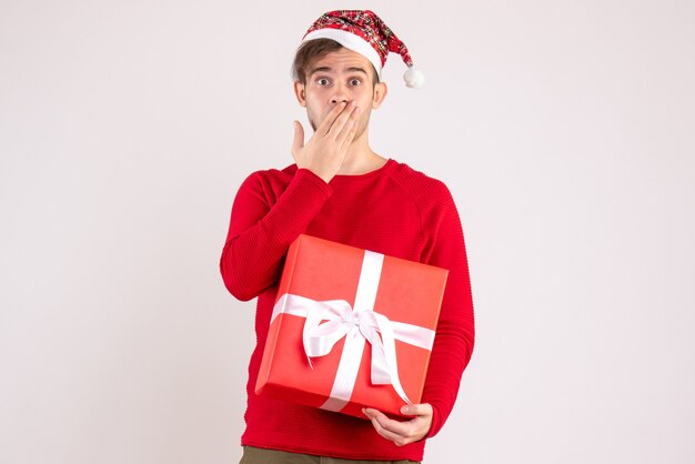 Vista frontal joven con gorro de Papá Noel de pie sobre fondo blanco espacio libre