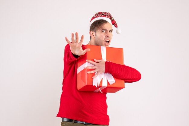 Vista frontal joven con gorro de Papá Noel con regalo sobre fondo blanco.
