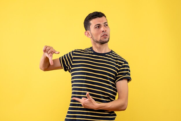 Vista frontal joven guapo en camiseta a rayas blanco y negro fondo amarillo aislado