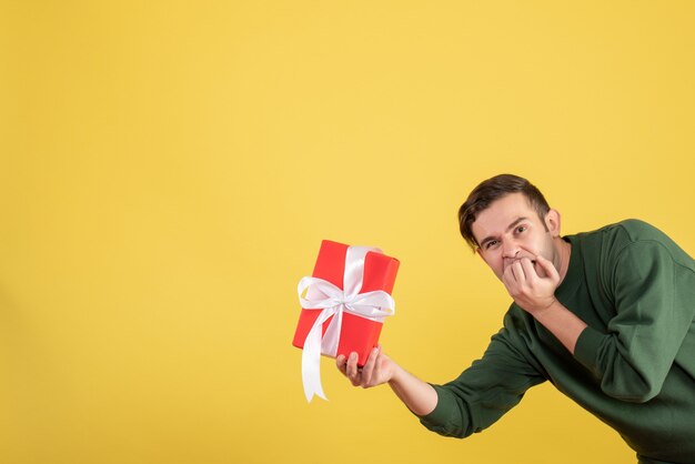 Vista frontal joven guapo con regalo en amarillo