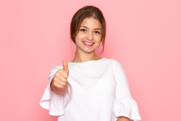 Una vista frontal joven hermosa mujer en camisa blanca posando con expresión feliz