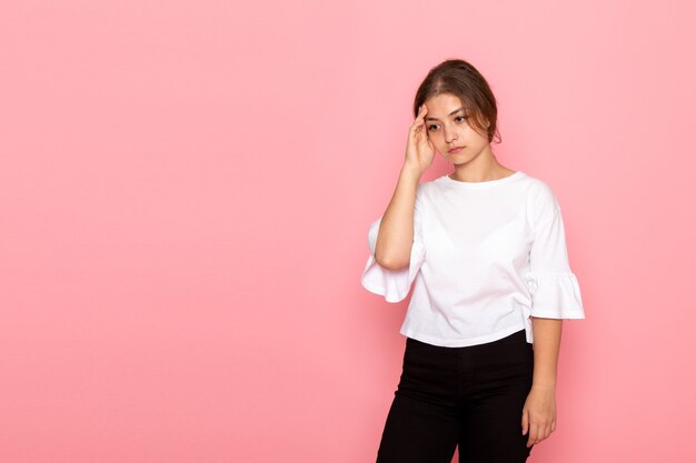 Una vista frontal joven hermosa mujer en camisa blanca posando con expresión de pensamiento