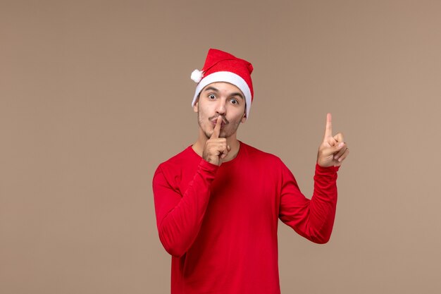 Vista frontal joven hombre pidiendo silencio sobre fondo marrón Navidad emoción vacaciones macho