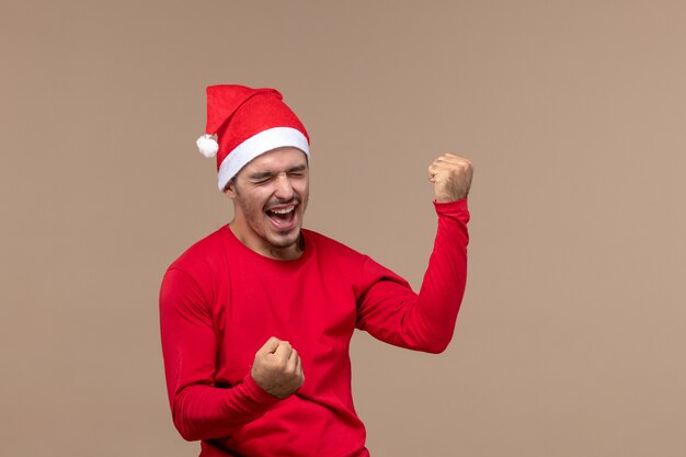 Vista frontal joven hombre sintiéndose feliz sobre fondo marrón emoción vacaciones macho