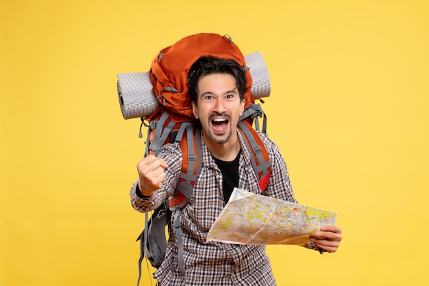 Vista frontal joven hombre yendo de excursión con mochila sosteniendo mapa sobre fondo amarillo viaje aire naturaleza empresa campus color