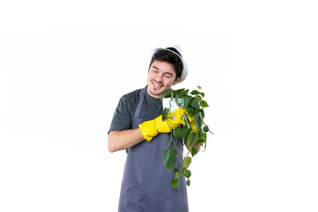 Vista frontal joven jardinero masculino sosteniendo la planta sobre fondo blanco jardín árbol tierra trabajo verde hierba color jardinero flor