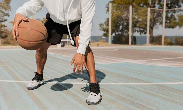 Vista frontal joven jugando baloncesto fuera