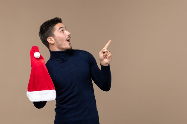 Vista frontal joven jugando con gorra roja en escritorio marrón emoción navidad año nuevo