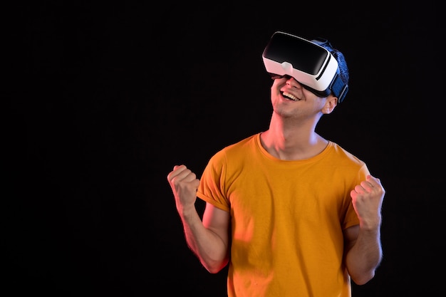 Vista frontal del joven jugando realidad virtual en la pared oscura
