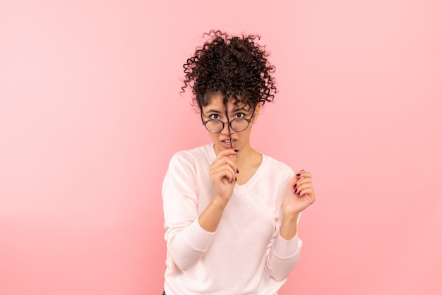 Foto gratuita vista frontal de la joven jugando con su cabello en la pared rosa