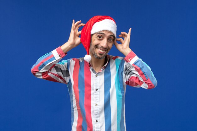 Vista frontal joven jugando con su gorra roja, emoción masculina de navidad