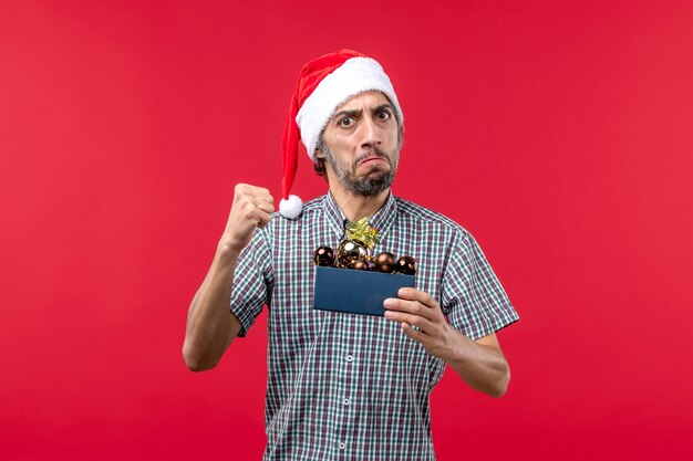 Vista frontal joven con juguetes de plástico en rojo piso emoción año nuevo navidad rojo