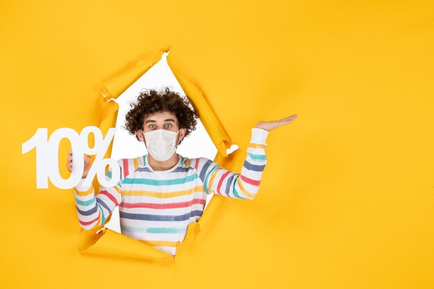 Vista frontal joven con máscara estéril con escritura en foto amarilla salud covid coronavirus venta