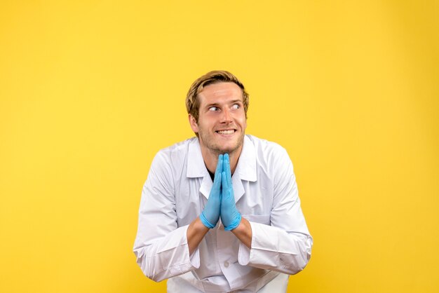 Vista frontal joven médico emocionado sobre fondo amarillo médico humano covid- pandemia