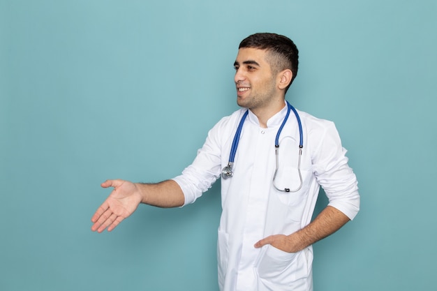 Vista frontal del joven médico en traje blanco con estetoscopio azul un apretón de manos