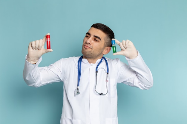 Vista frontal del joven médico en traje blanco con estetoscopio azul sosteniendo frascos