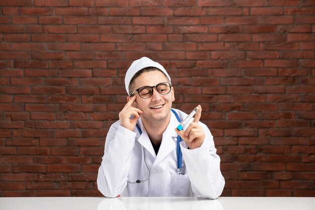 Vista frontal joven médico en traje médico blanco con matraz pequeño