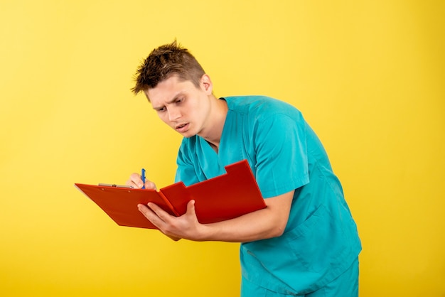 Vista frontal joven médico en traje médico con notas sobre amarillo